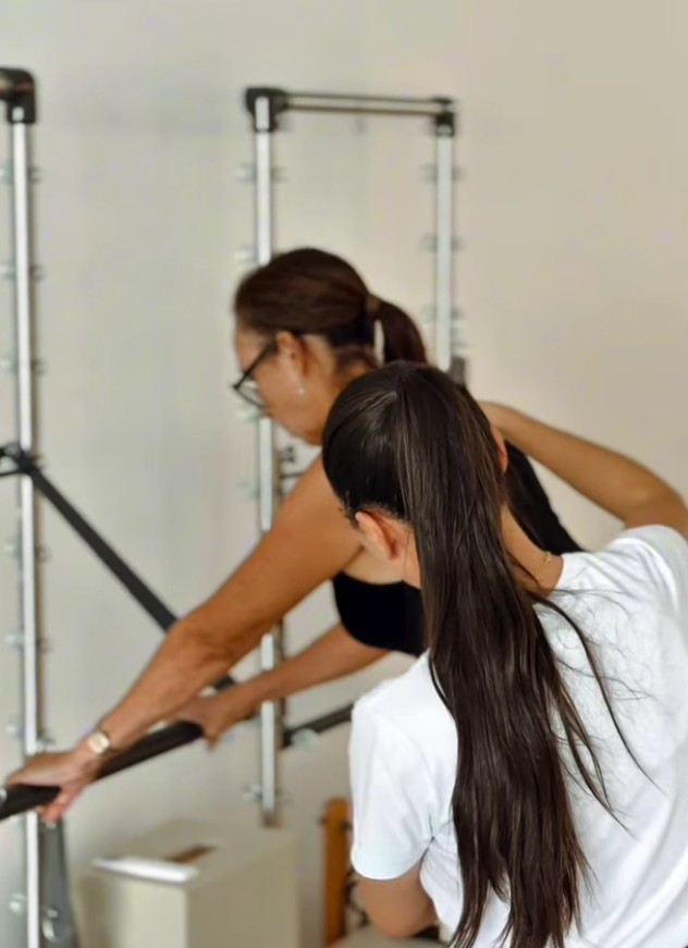 Instrutora acompanhando aluna em aula de Pilates no estúdio